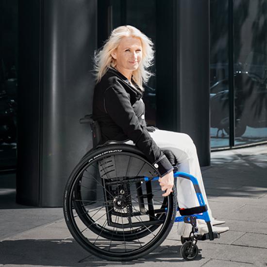 Side view of lady sat in Kuschall Compact 2.0 wheelchair in black and blue